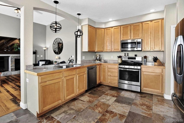 30889 Manitoba Dr, Evergreen, CO 80439 - kitchen with stainless steel appliances, stone tile flooring, hanging light fixtures, a peninsula, and light brown cabinetry