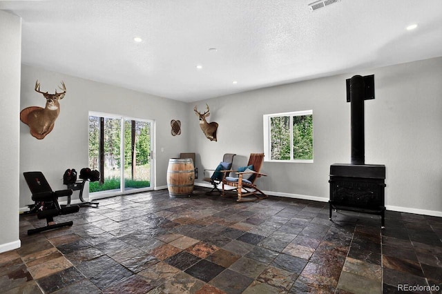 30889 Manitoba Dr, Evergreen, CO 80439 - sitting room with plenty of natural light, recessed lighting, stone tile flooring, a wood stove, and a textured ceiling