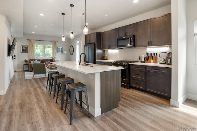 4184 Kalamath St, Denver, CO 80211 - kitchen featuring appliances with stainless steel finishes, a kitchen breakfast bar, dark brown cabinets, light wood finished floors, and recessed lighting