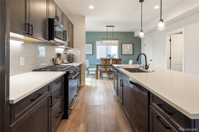 4184 Kalamath St, Denver, CO 80211 - kitchen with stainless steel appliances, a sink, light wood-type flooring, tasteful backsplash, and dark brown cabinets