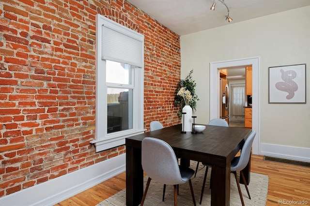 2527 W Dunkeld Pl, Denver, CO 80211 - dining space with light wood finished floors and brick wall