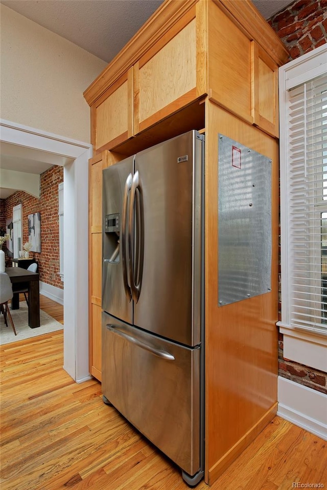 2527 W Dunkeld Pl, Denver, CO 80211 - kitchen featuring stainless steel fridge, light wood-style flooring, and brick wall