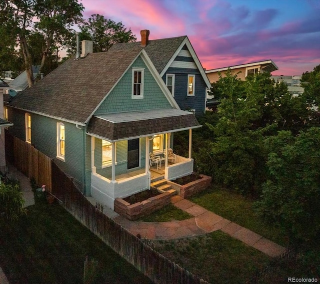 2527 W Dunkeld Pl, Denver, CO 80211 - view of front facade with a chimney, covered porch, and roof with shingles