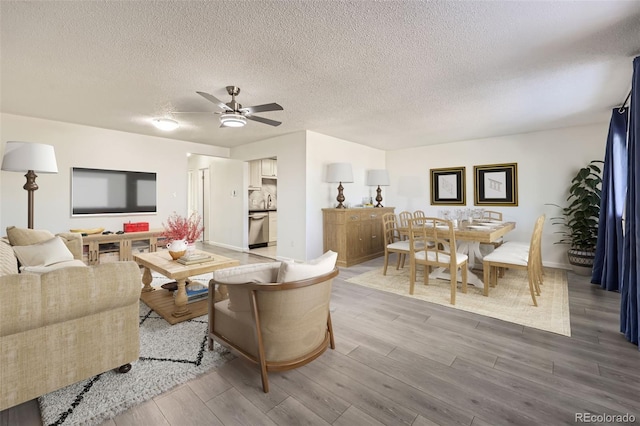 living room with a textured ceiling, light wood-type flooring, and ceiling fan