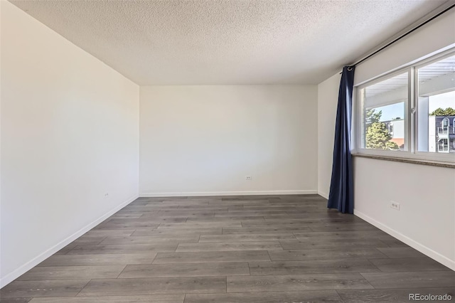 unfurnished room featuring a textured ceiling and dark hardwood / wood-style floors