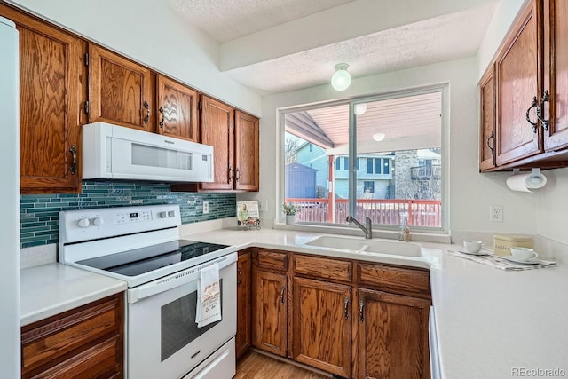 kitchen featuring sink, decorative backsplash, white appliances, and a textured ceiling