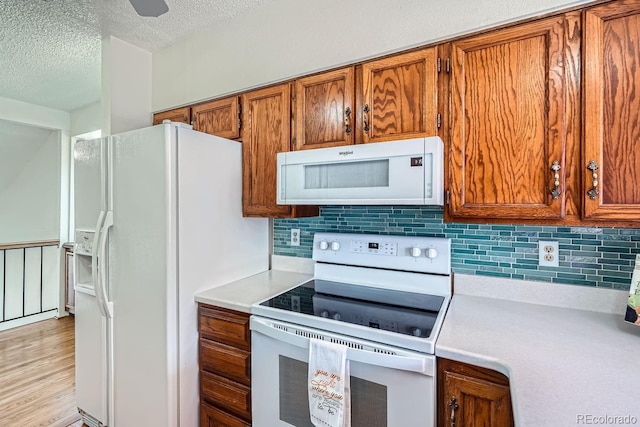 kitchen featuring white appliances, a textured ceiling, and backsplash