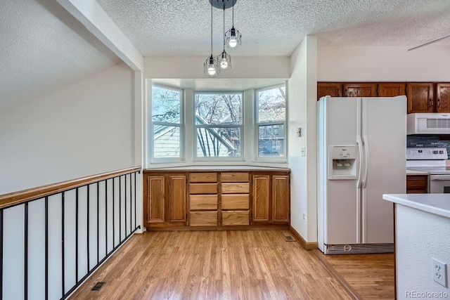 kitchen with a textured ceiling, white appliances, light wood-type flooring, backsplash, and hanging light fixtures