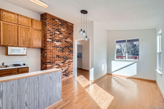 kitchen featuring decorative light fixtures, a textured ceiling, and light hardwood / wood-style floors