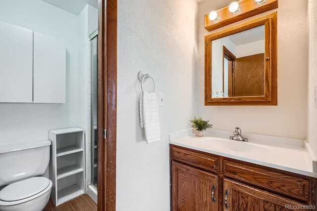 bathroom featuring toilet, a shower with shower door, and vanity