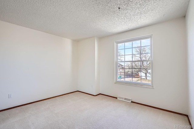 carpeted empty room with a textured ceiling