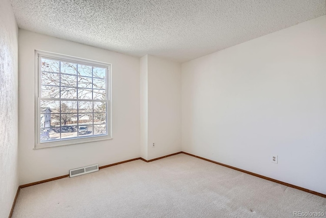 carpeted empty room with a textured ceiling