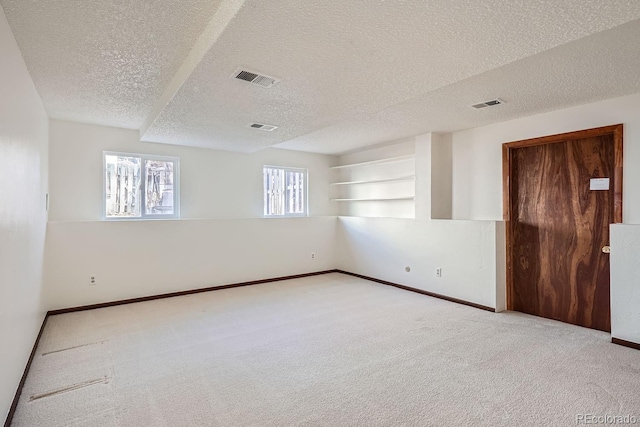 carpeted spare room with a textured ceiling and built in features