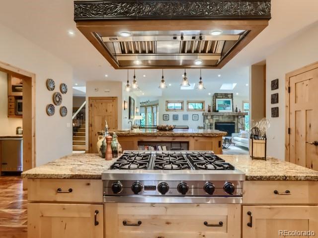 3135 11th St, Boulder, CO 80304 - kitchen with stainless steel gas cooktop, open floor plan, light brown cabinets, light stone counters, and a fireplace