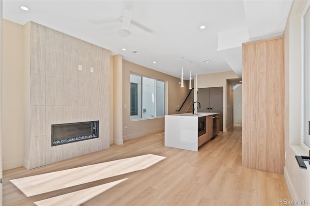 unfurnished living room with a fireplace, light hardwood / wood-style floors, and sink