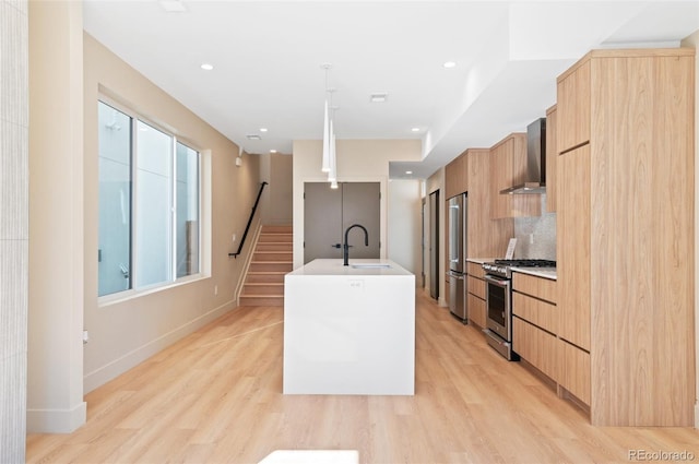 kitchen with wall chimney exhaust hood, light wood-type flooring, tasteful backsplash, a kitchen island with sink, and high end appliances