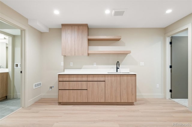 kitchen with sink, light hardwood / wood-style flooring, and light brown cabinetry