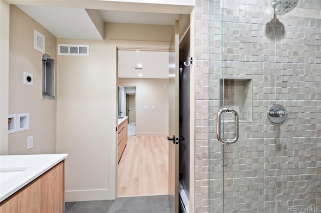 bathroom featuring a shower with shower door and vanity