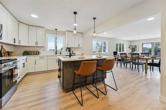 3533 Saguaro Cir, Colorado Springs, CO 80925 - kitchen featuring appliances with stainless steel finishes, light wood-style flooring, white cabinets, a center island with sink, and recessed lighting