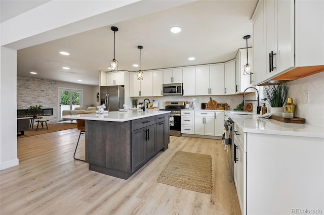 3533 Saguaro Cir, Colorado Springs, CO 80925 - kitchen featuring appliances with stainless steel finishes, white cabinetry, light wood-style floors, light countertops, and hanging light fixtures