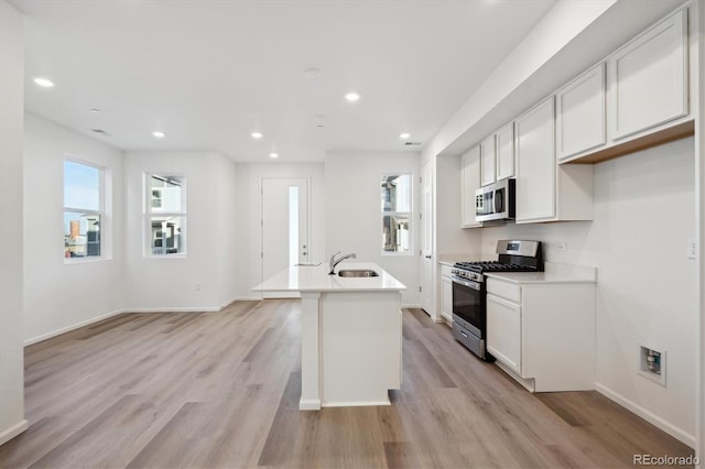 kitchen with recessed lighting, stainless steel appliances, a sink, white cabinets, and light wood-type flooring