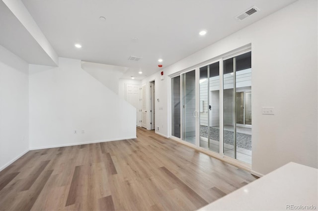 spare room featuring baseboards, wood finished floors, visible vents, and a healthy amount of sunlight