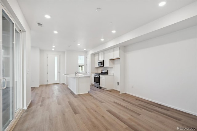 kitchen featuring visible vents, white cabinets, light wood-style flooring, stainless steel appliances, and a sink