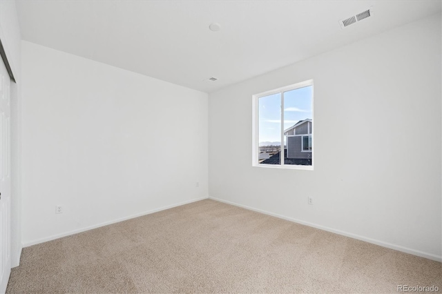 carpeted empty room featuring visible vents and baseboards