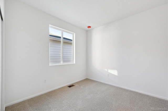 carpeted spare room featuring baseboards and visible vents