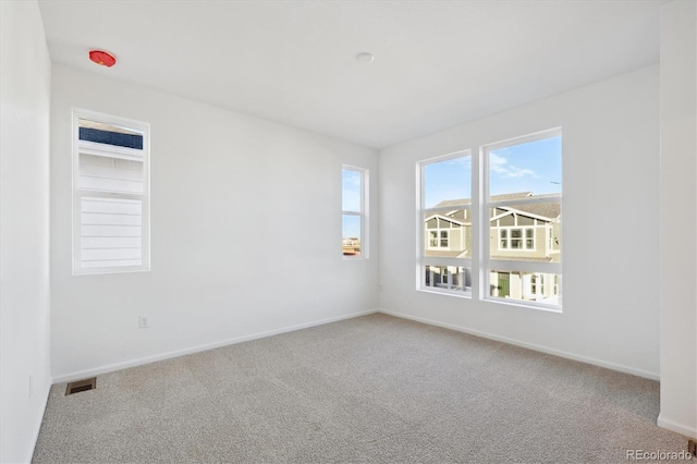 spare room featuring carpet floors, baseboards, and visible vents