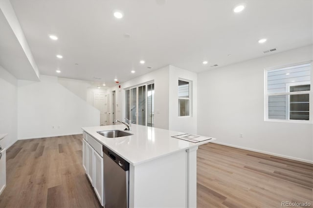 kitchen featuring white cabinetry, sink, light hardwood / wood-style flooring, stainless steel dishwasher, and a center island with sink