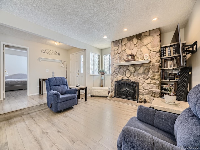 living room featuring a textured ceiling, a fireplace, and hardwood / wood-style flooring