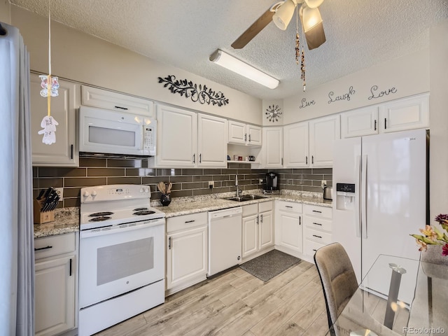 kitchen with white cabinets, sink, white appliances, and a textured ceiling