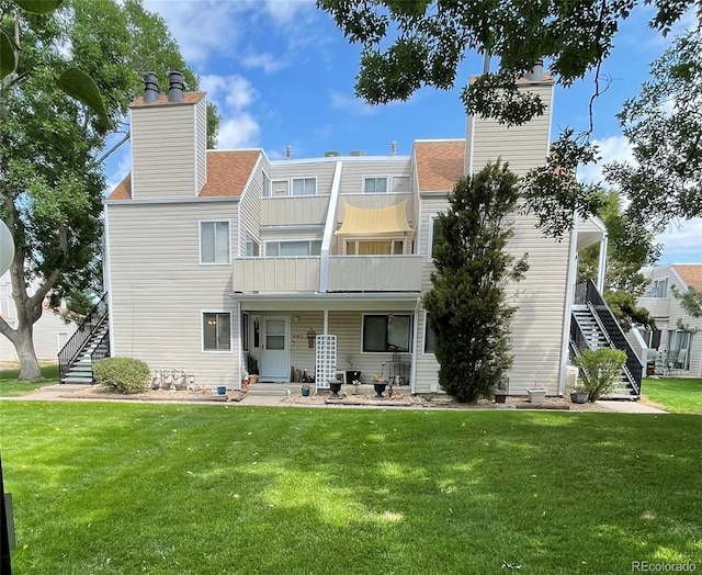 rear view of house with a balcony and a lawn