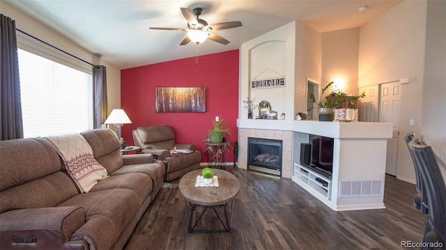 living room featuring lofted ceiling, ceiling fan, dark wood finished floors, a fireplace, and baseboards