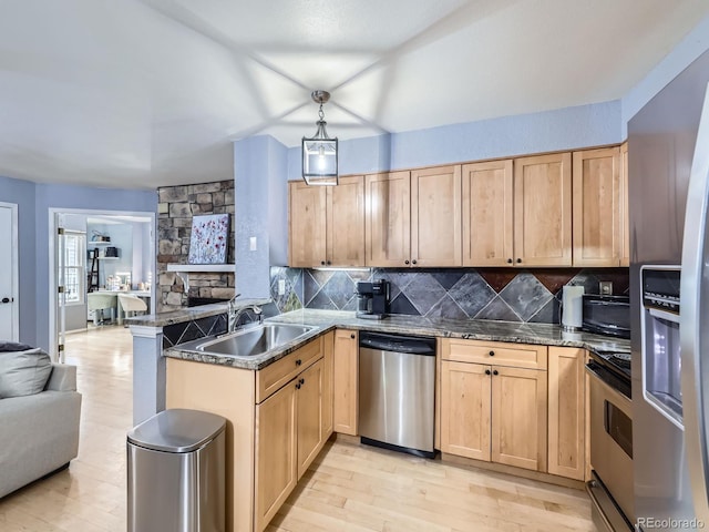 kitchen featuring sink, hanging light fixtures, kitchen peninsula, appliances with stainless steel finishes, and light wood-type flooring