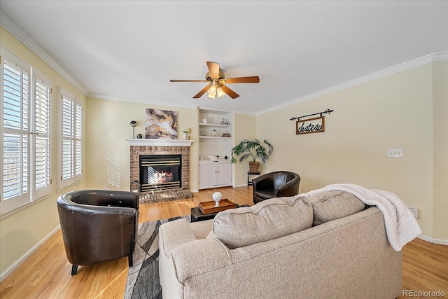 living room featuring crown molding, a brick fireplace, hardwood / wood-style flooring, and ceiling fan