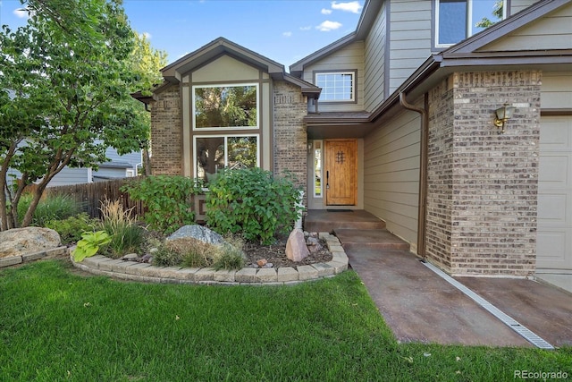 doorway to property with a garage and a lawn