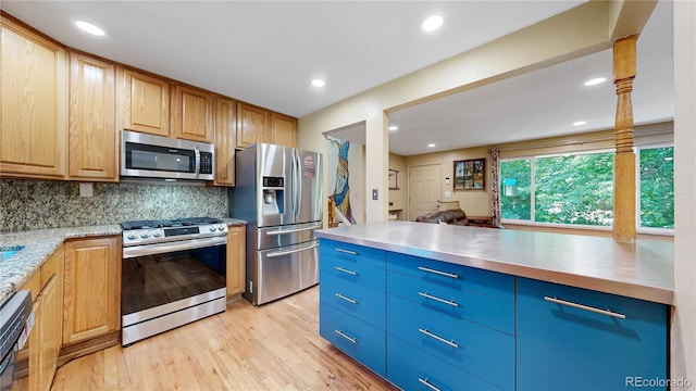 kitchen featuring decorative backsplash, light stone countertops, stainless steel appliances, and light hardwood / wood-style flooring