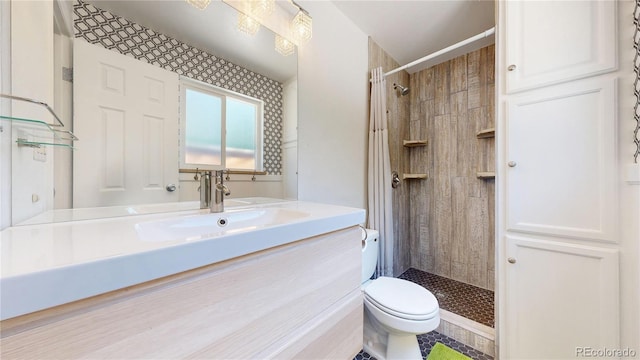 bathroom with toilet, vanity, and tiled shower