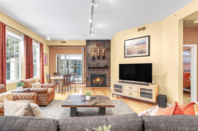 living room with a textured ceiling, a fireplace, wood finished floors, and visible vents