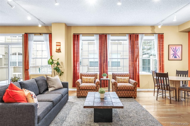 living room with a textured ceiling, baseboards, and wood finished floors