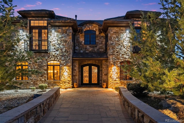 property entrance with stone siding and a balcony