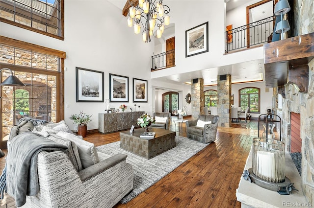 living area featuring a chandelier, a high ceiling, baseboards, wood-type flooring, and arched walkways
