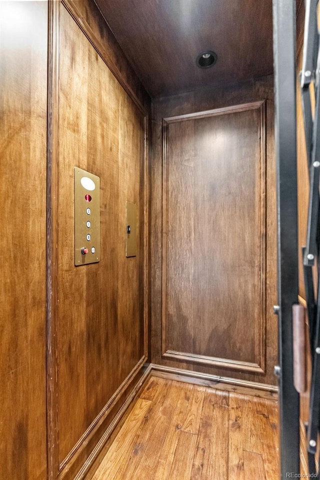elevator with wood finished floors and wood walls