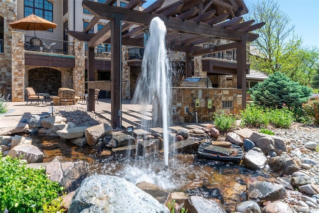 view of patio / terrace with an outdoor kitchen, a small pond, and a pergola