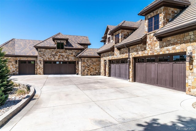 view of front facade with stone siding, concrete driveway, and a garage