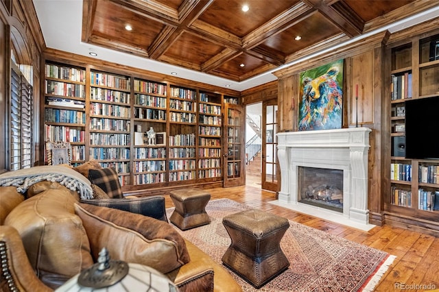 living area featuring wooden walls, coffered ceiling, ornamental molding, hardwood / wood-style floors, and built in features