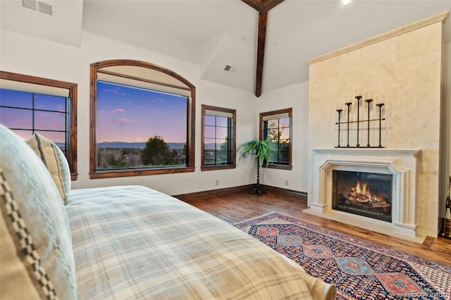 bedroom featuring wood finished floors, a fireplace with flush hearth, and baseboards