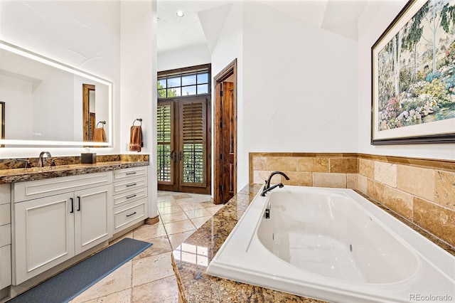 bathroom with vanity, a garden tub, and stone tile flooring